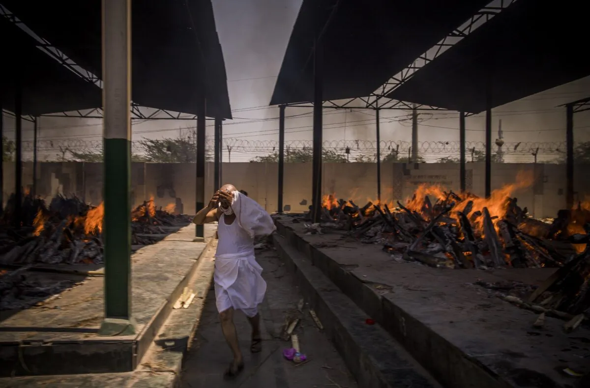 A priest who helps perform last rites runs while covering his face amid the multiple funeral pyres of people who died of COVID-19, at a crematorium in New Delhi, India, on April 24, 2021. (Anindito Mukherjee/Getty Images)