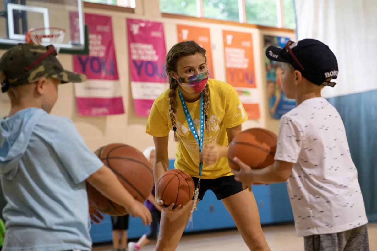 A counselor wearing a protective face mask plays with children as summer camps reopen amid the COVID-19 spread at Carls Family YMCA summer camp in Milford, Mich., on June 23, 2020. (Emily Elconin/Reuters)