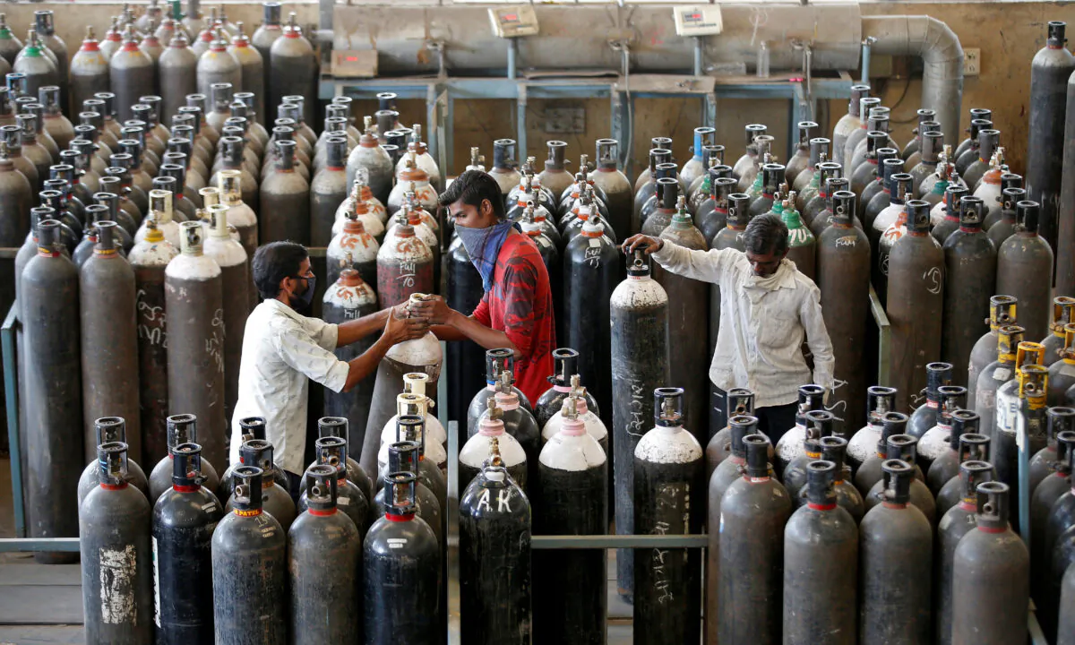 People carry oxygen cylinders after refilling them in a factory, amidst the spread of the CCP virus disease (COVID-19) in Ahmedabad, India, on April 25, 2021. (Amit Dave/Reuters)