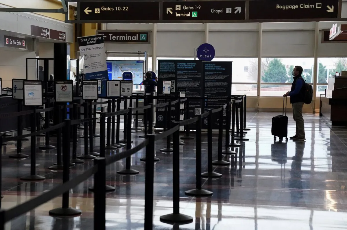 A Christmas week traveler stands by a security gate at Ronald Reagan Washington National Airport, in Arlington, Virginia, U.S., Dec. 22, 2020. (Reuters/Kevin Lamarque)
