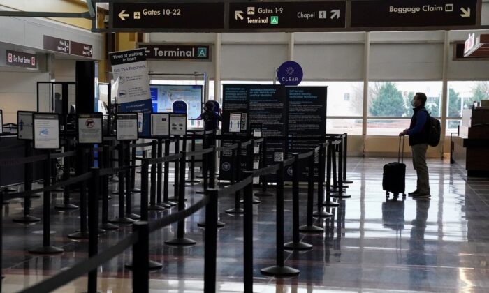 A Christmas week traveler stands by a security gate at Ronald Reagan Washington National Airport, in Arlington, Virginia, U.S., Dec. 22, 2020.  (Reuters/Kevin Lamarque)