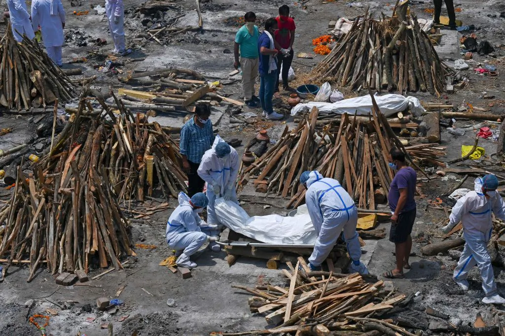 Family members and ambulance workers wearing PPE kit (Personal Protection Equipment) carry the bodies of the patients who died of COVID-19 at a cremation ground in New Delhi, India, on April 27, 2021. (Prakash Singh/AFP via Getty Images)
