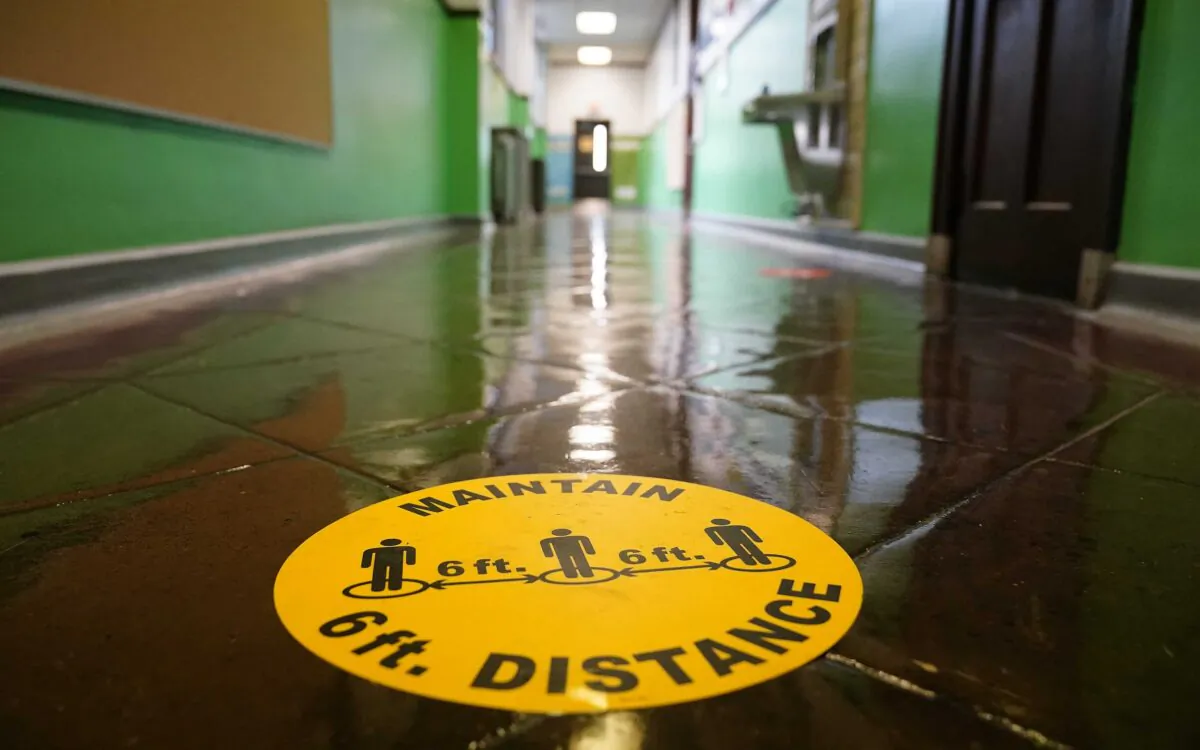 A social distancing reminder is posted on a hallway floor of Nebinger Elementary School in Philadelphia, Pa., on March 19, 2021. (Matt Rourke/AP Photo)