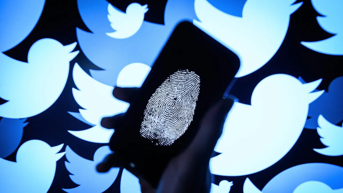 A thumbprint is displayed on a mobile phone as the logo for the Twitter social media network is projected onto a screen in London, England on Aug. 9, 2017. (Leon Neal/Getty Images)