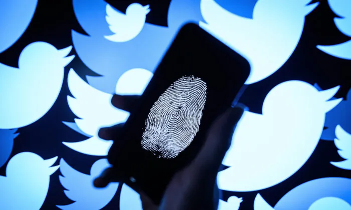 A thumbprint is displayed on a mobile phone as the logo for the Twitter social media network is projected onto a screen in London, England on Aug. 9, 2017. (Leon Neal/Getty Images)