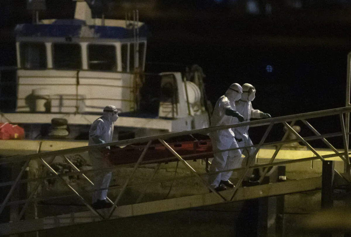 Emergency services carry dead bodies of migrants after being recovered from a wooden boat at the port of Los Cristianos in the south of Tenerife, in the Canary Island, Spain, on April 28, 2021. (Andres Gutierrez/AP Photo)
