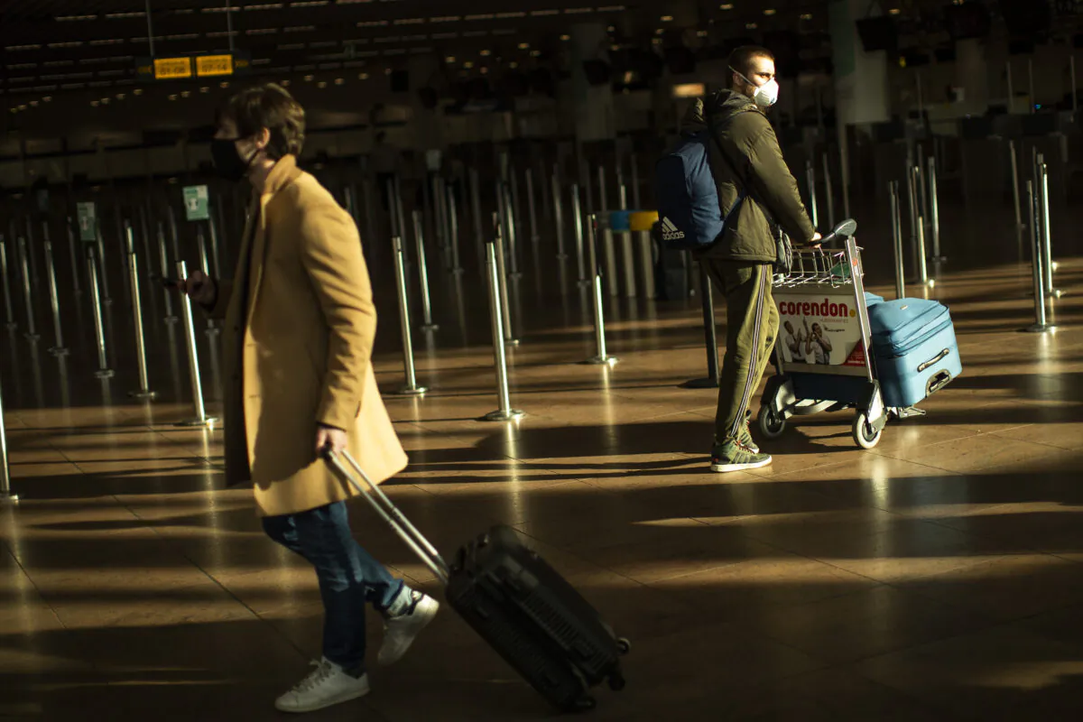 Travellers, wearing face masks to prevent the spread of the coronavirus COVID-19, walk along the departure hall of the Zaventem international airport in Brussels, on Jan. 22, 2021. (Francisco Seco/AP Photo)