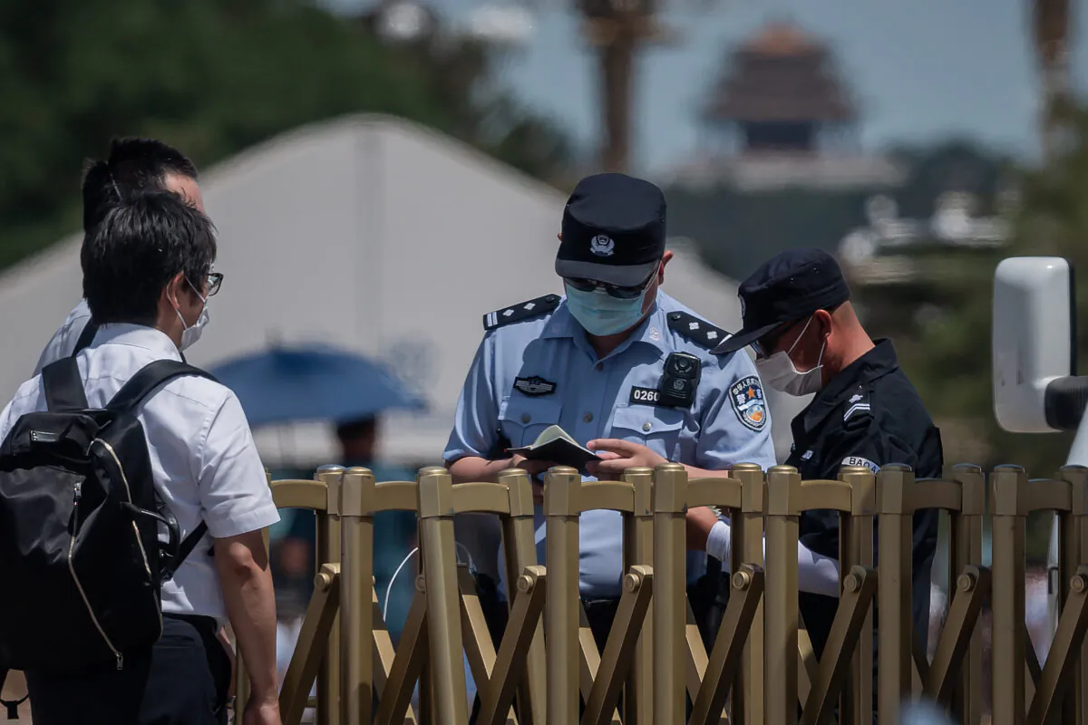 Police officers (R) check the passport of a foreigner (L) at a security gate of an entrance to Tiananmen Square in Beijing on June 4, 2020. (NICOLAS ASFOURI/AFP via Getty Images)