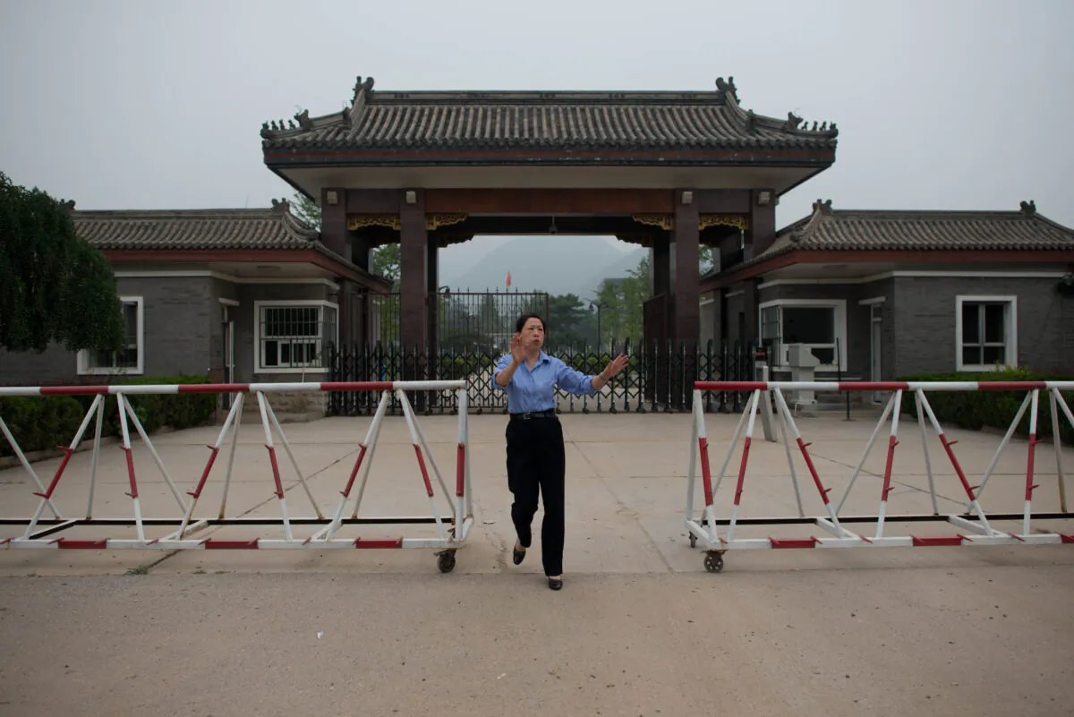 A policewoman approaches to stop the taking of photos at the entrance to Qincheng prison on the outskirts of Beijing on Sept. 12, 2013. (Ed Jones/AFP via Getty Images)