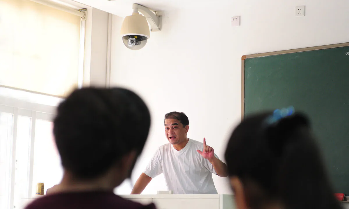 Ilham Tohti, a Uyghur professor of economics, delivers his lecture under a security surveillance camera mounted above the teacher's podium in a classroom in Beijing on June 12, 2010. Tohti was sentenced to life imprisonment in 2014 on charges of inciting separatism, and his family lost all contact with him in 2017. (Frederic J. Brown/AFP via Getty Images)