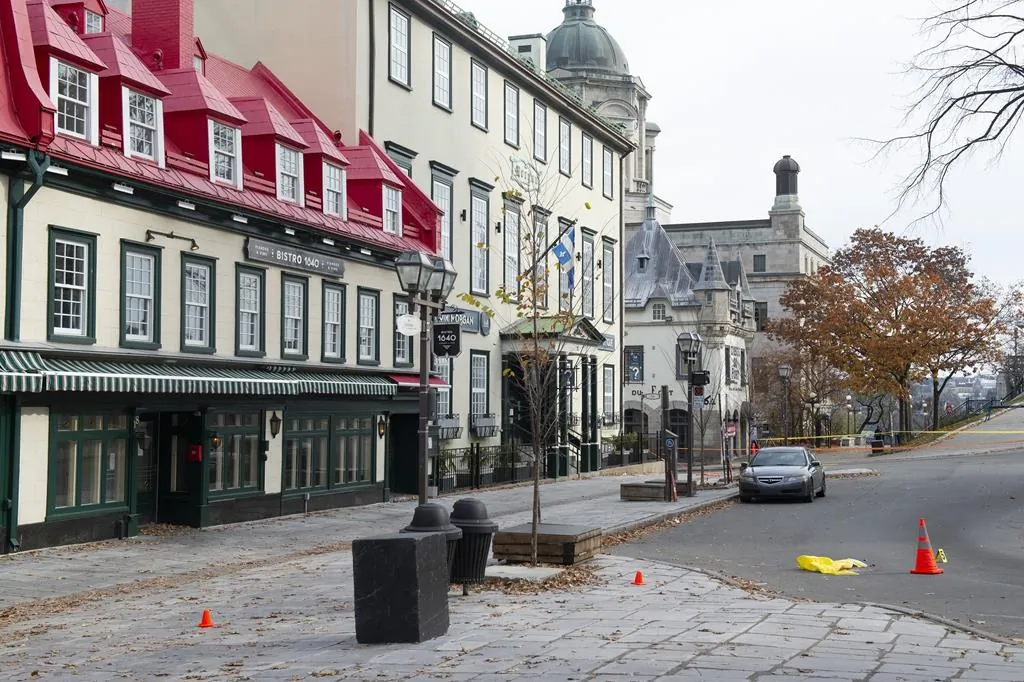 A bloodied yellow sheet marking the site of a victim of a stabbing is seen beside an evidence marker in Quebec City, on Nov. 1, 2020. The man accused in the Quebec City Halloween night stabbing attack that killed two people appeared in court today via videoconference from the infirmary of his detention centre. (The Canadian Press/Jacques Boissinot)