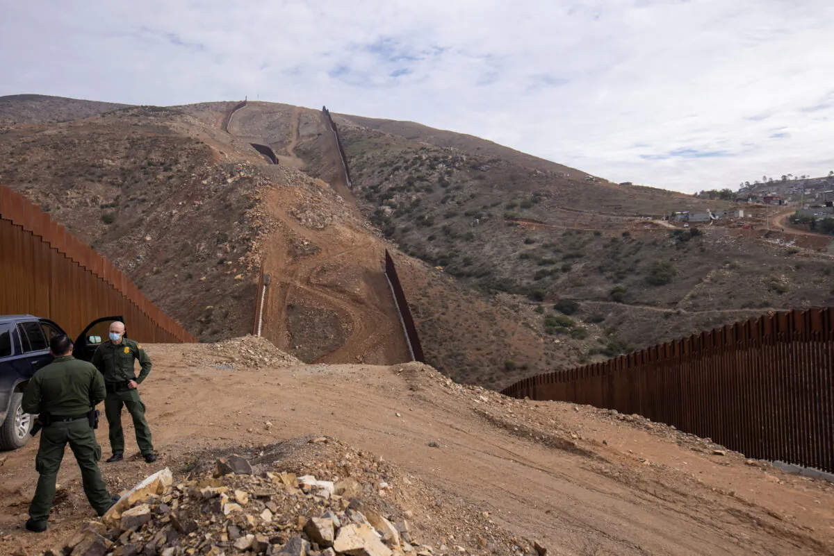 Border patrol agents stand near the location of halted construction along the U.S. Border wall with Mexico as an unfinished section is shown on Otay Mountain, east of San Diego, Calif., on Feb. 2, 2021. (Mike Blake/Reuters)