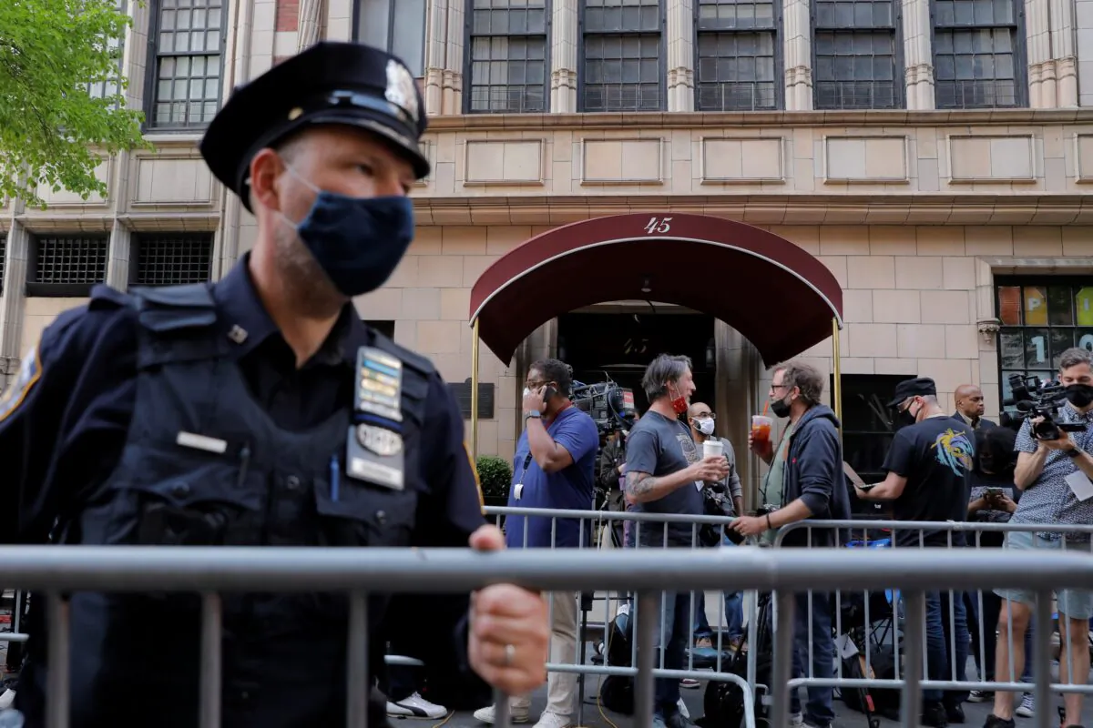 An officer from the New York Police Department places barricades outside the apartment building of former New York City Mayor Rudy Giuliani, personal attorney to former President Donald Trump, in New York City, on April 28, 2021. (Andrew Kelly/Reuters)