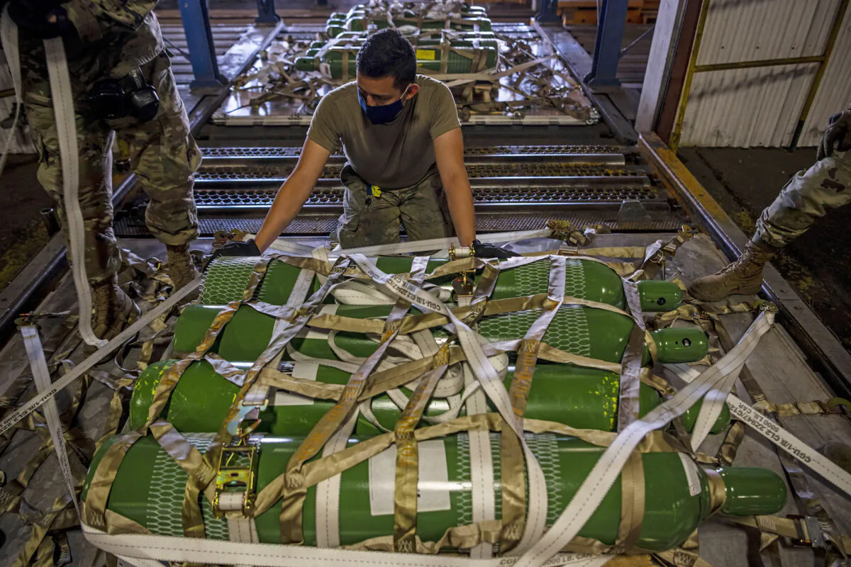 In this photo provided by the U.S. Air Force, Airman 1st Class Fernando Beltran, secures oxygen cylinders to a pallet on April 28, 2021, at Travis Air Force Base in California. (Nicholas Pilch/U.S. Air Force via AP)