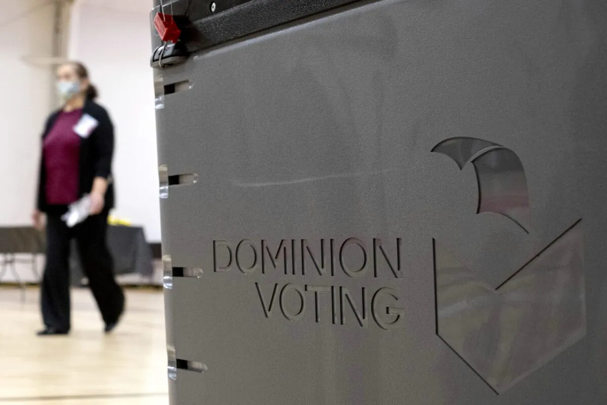 A worker passes a Dominion Voting ballot scanner while setting up a polling location at an elementary school in Gwinnett County, Ga., outside of Atlanta on Jan. 4, 2021. (Ben Gray/AP Photo)