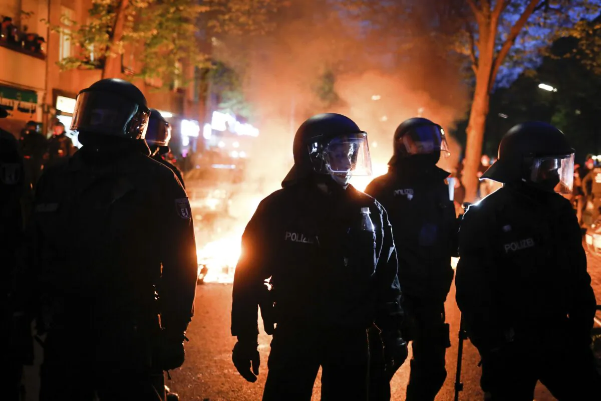 Police officers stand in front of a fire set up by demonstrators during a May Day rally in Berlin, Germany, on May 1, 2021. (Markus Schreiber/AP Photo)