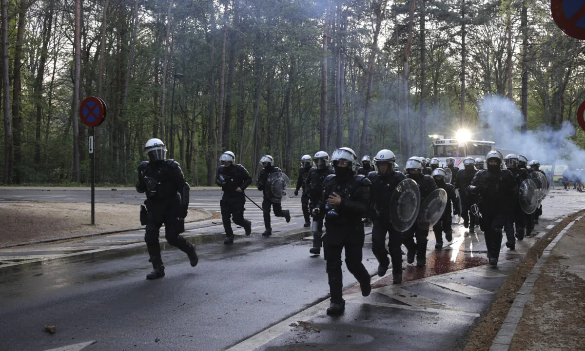 A group of police run down the street in the Bois de la Cambre park during a party called "La Boum 2" in Brussels, Saturday, May 1, 2021.  (Olivier Matthys/AP Photo)