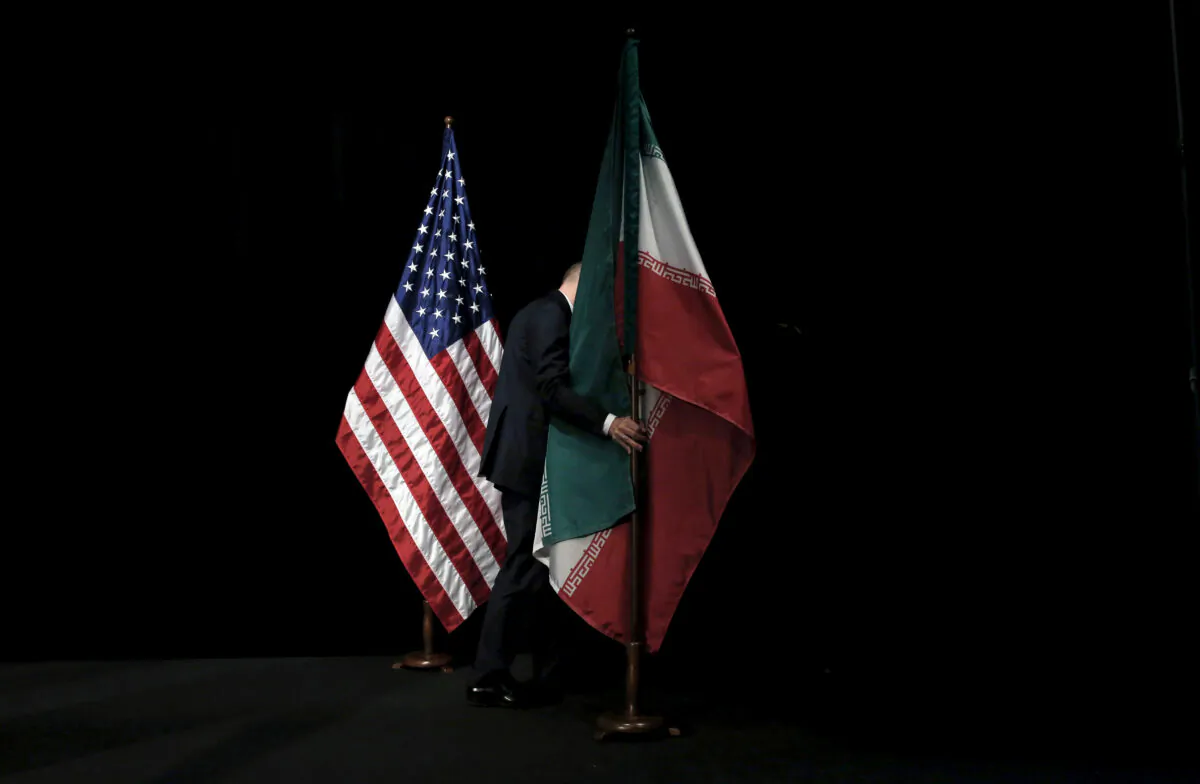 A staff member removes the Iranian flag from the stage after a group picture with foreign ministers and representatives of the U.S., Iran, China, Russia, Britain, Germany, France and the European Union during the Iran nuclear talks at the Vienna International Center in Vienna, Austria, on July 14, 2015. (Carlos Barria/Reuters)