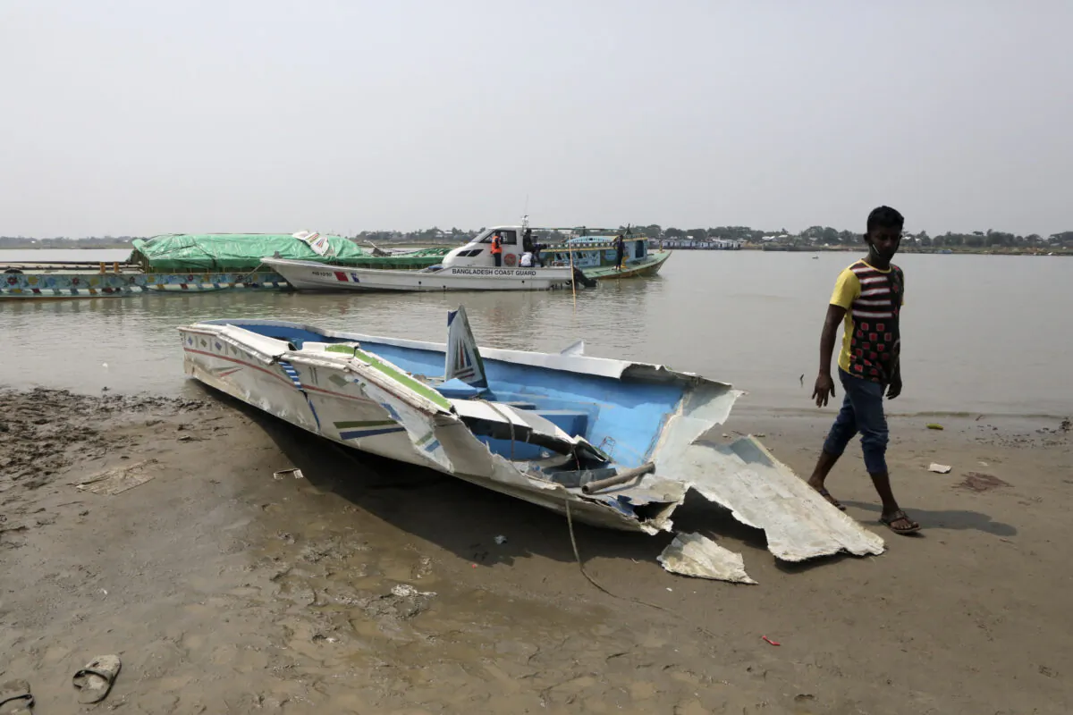 A man walks past the mangled remains of a speedboat that overturned in River Padma at the Kanthalbari ferry terminal in Madaripur, central Bangladesh, on  May 3, 2021. (Abdul Goni/AP Photo)