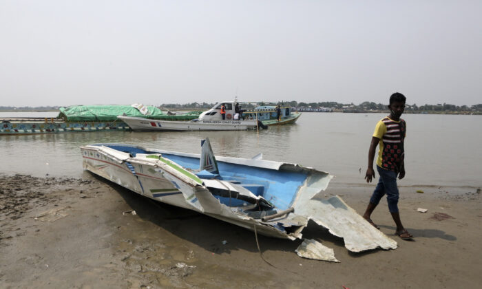 A man walks past the mangled remains of a speedboat that overturned in River Padma at the Kanthalbari ferry terminal in Madaripur, central Bangladesh, on  May 3, 2021. (Abdul Goni/AP Photo)