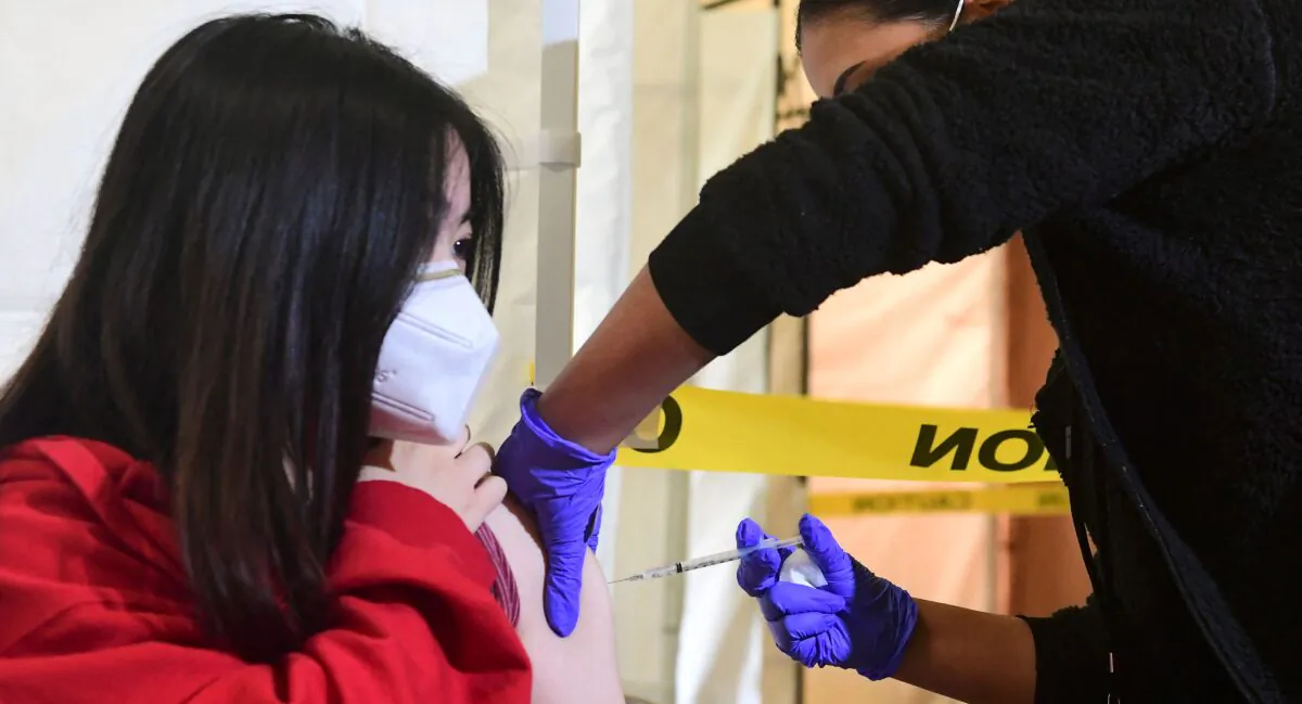 High school student, 17, receives her first Pfizer COVID-19 vaccine administered by Medical Assistants from St. John's Well Child and Family Center at Abraham Lincoln High School in Los Angeles on April 23, 2021. (Frederic J. Brown/AFP via Getty Images)
