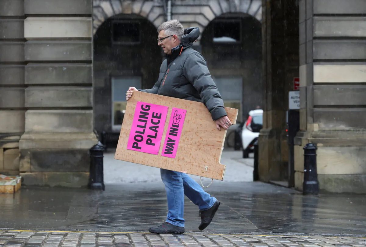 A council staff member carries a sign during preparations to deliver ballot boxes to polling stations ahead of Scottish parliamentary election held on May 6, at the Royal Mile, Edinburgh, Scotland, Britain, on May 4, 2021. (Russell Cheyne/Reuters)