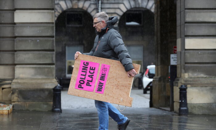 A council staff member carries a sign during preparations to deliver ballot boxes to polling stations ahead of Scottish parliamentary election held on May 6, at the Royal Mile, Edinburgh, Scotland, Britain, on May 4, 2021. (Russell Cheyne/Reuters)
