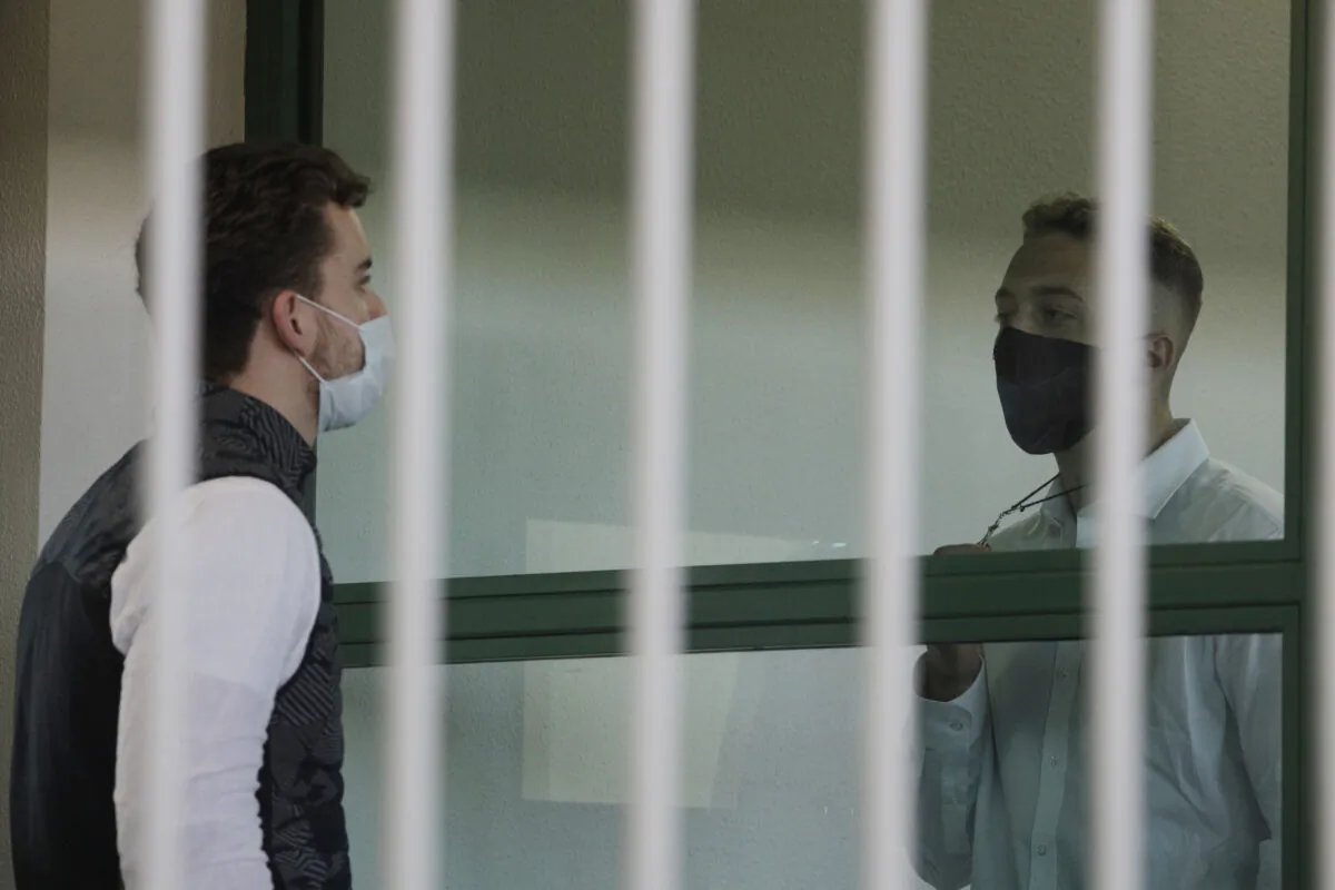 Finnegan Lee Elder (R) shows a crucifix to co-defendant Gabriel Natale-Hjorth before a jury began deliberating their fate in their trial for the slaying of an Italian plainclothes police officer on a street near the hotel where they were staying while on vacation in Rome in summer 2019, in Rome, on May 5, 2021. (Gregorio Borgia/AP Photo)