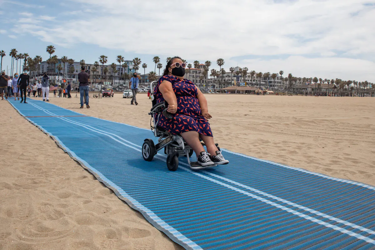 The City of Huntington Beach, Calif., celebrates the release of its first Mobi-Mat, a wheelchair accessible pathway that leads from the boardwalk to the ocean, on May 5, 2021. (John Fredricks/The Epoch Times)