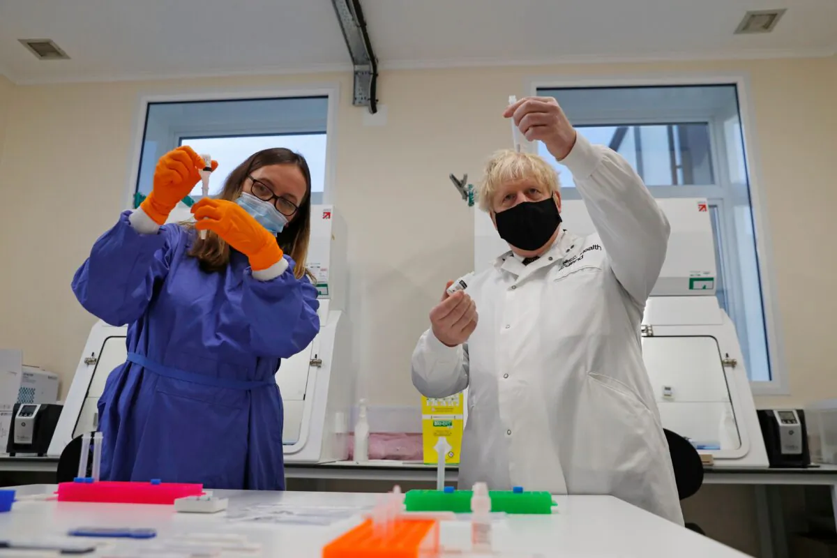 Britain's Prime Minister Boris Johnson looks at samples at the Lateral Flow Testing Laboratory with Doctor Abbie Bown during a visit to the Public Health England site at Porton Down science park near Salisbury, southern England, on Nov. 27, 2020. (Adrian Dennis/AFP via Getty Images)