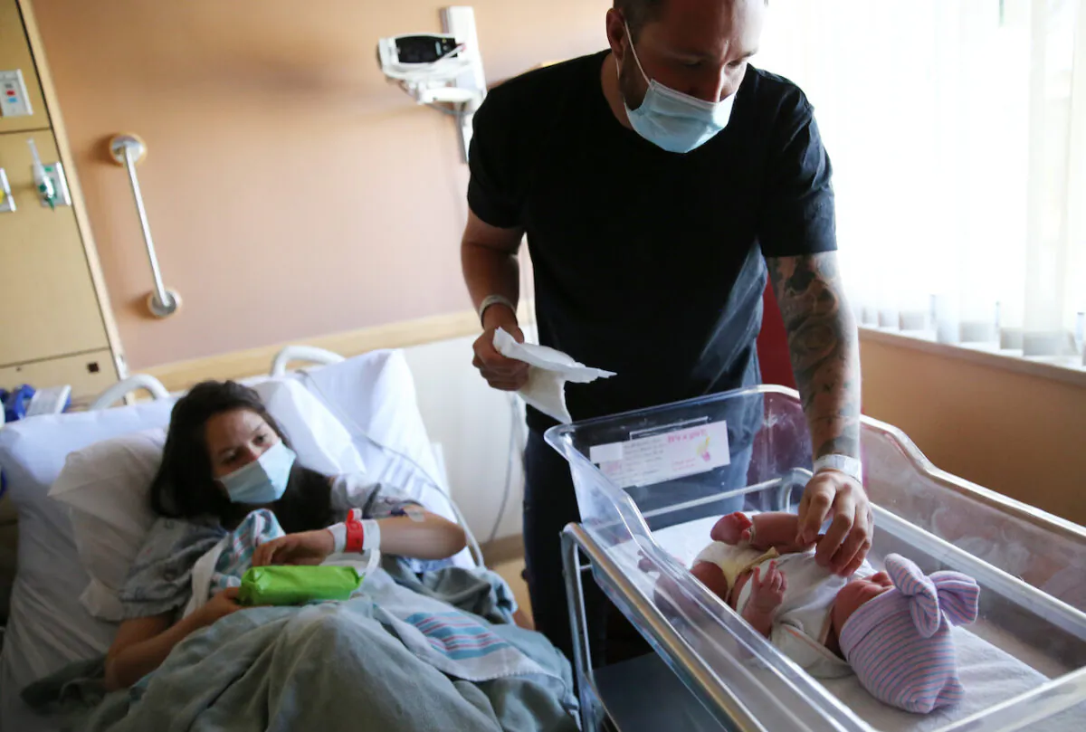 A father prepares to change the diaper of his newborn daughter as his wife keeps watch in the postpartum unit at Providence St. Mary Medical Center in Apple Valley, Calif., on March 30, 2021. (Mario Tama/Getty Images)