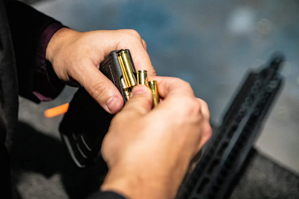 A man loads .223-caliber bullets into an AR-15 rifle magazine at FT3 tactical shooting range in Stanton, Calif., on May 3, 2021. (John Fredricks/The Epoch Times)