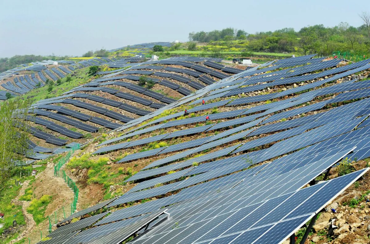 Chinese workers check solar photovoltaic modules on a hillside in a village in Chuzhou, in eastern China's Anhui Province, on April 13, 2017. (STR/AFP via Getty Images)