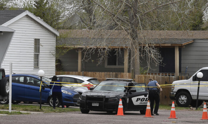 A Colorado Springs police officer goes to help a person who was in a different mobile home to be able to get to her car from behind the crime tape in Colorado Springs, Colo., on May 9, 2021. A gunman opened fire at a birthday party in Colorado, slaying six adults before killing himself Sunday. (Jerilee Bennett/The Colorado Springs Gazette via AP)