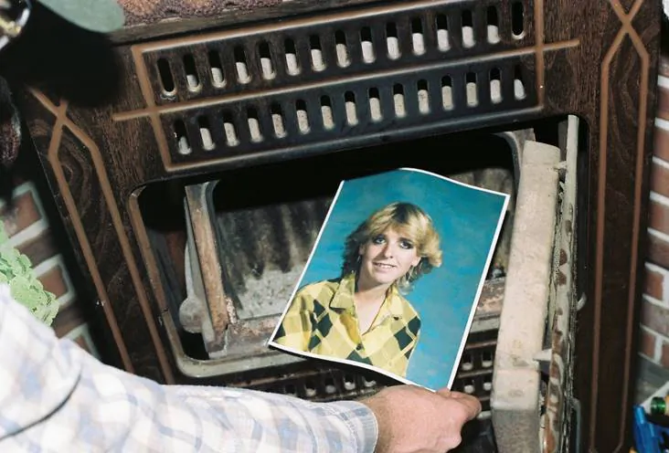 A law enforcement official discovers a photograph of Pamela Pitts in the wood stove of a home she shared with two others in Prescott, Ariz., in 1988. (Yavapai County Sheriff's Office via AP)