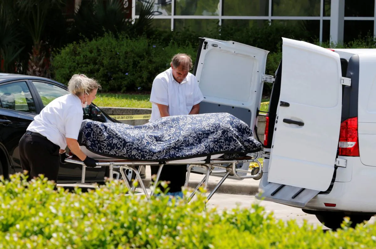 Officials move a body at the site of a fatal shooting outside a U.S. Customs and Immigration Service building in Orlando, Fla., on May 10, 2021.  (Joe Skipper/Reuters)