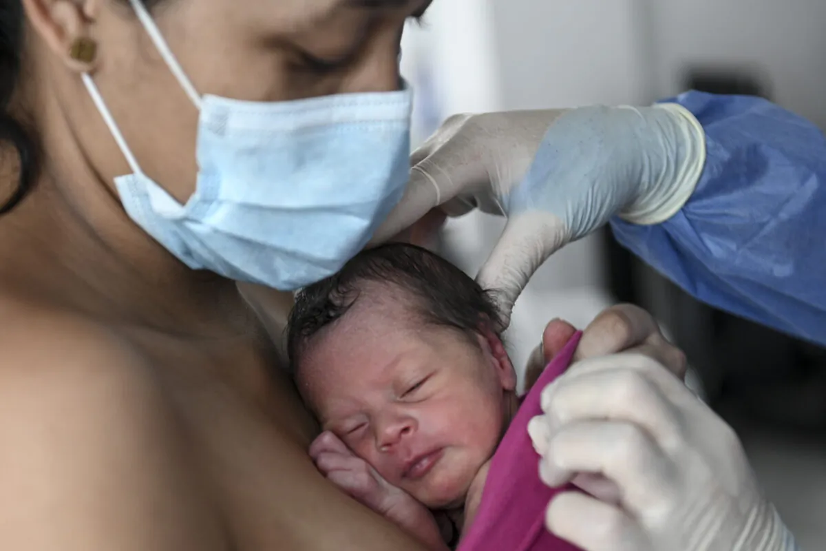 A mother carries her newly born baby as a doctor helps her at the Medellin General Hospital, in Medellin, Colombia, on May 21, 2020. (Joaquin Sarmiento/AFP via Getty Images)