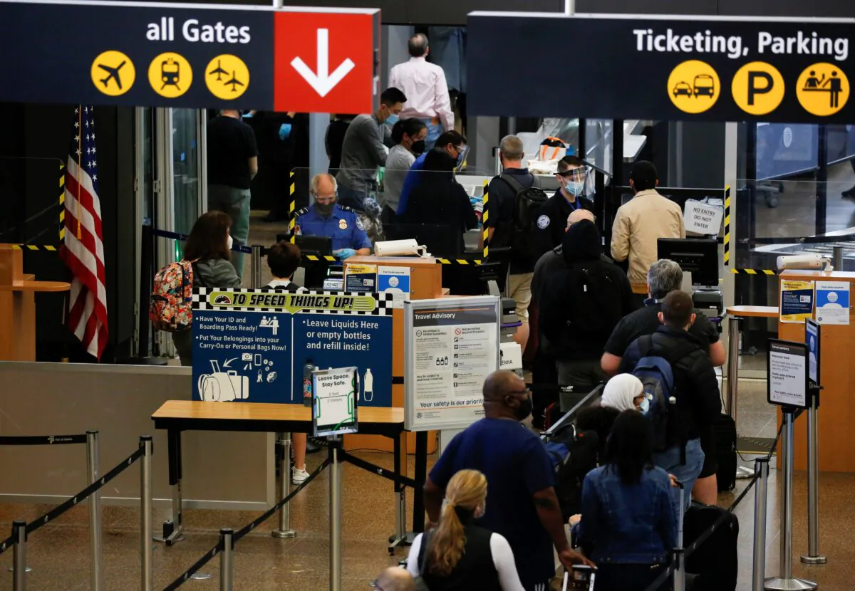 Travelers queue in a security line limited to every other lane for social distancing at Seattle-Tacoma International Airport in SeaTac, Wash., on April 12, 2021.  (Lindsey Wasson/Reuters)