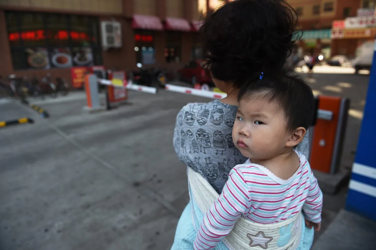 A woman carrying a baby in Yanji, Jilin Province, China, on June 24, 2015. (Greg Baker/AFP via Getty Images)
