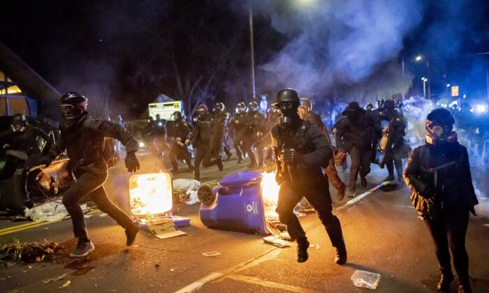 Portland police officers chase demonstrators after a riot was declared in Portland, Ore., on April 12, 2021. (Nathan Howard/Getty Images)