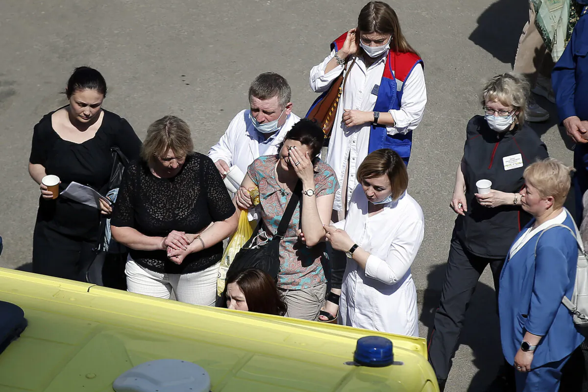 Medics and friends help a woman board an ambulance at a school after a shooting in Kazan, Russia, on May 11, 2021. (Roman Kruchinin/AP Photo)