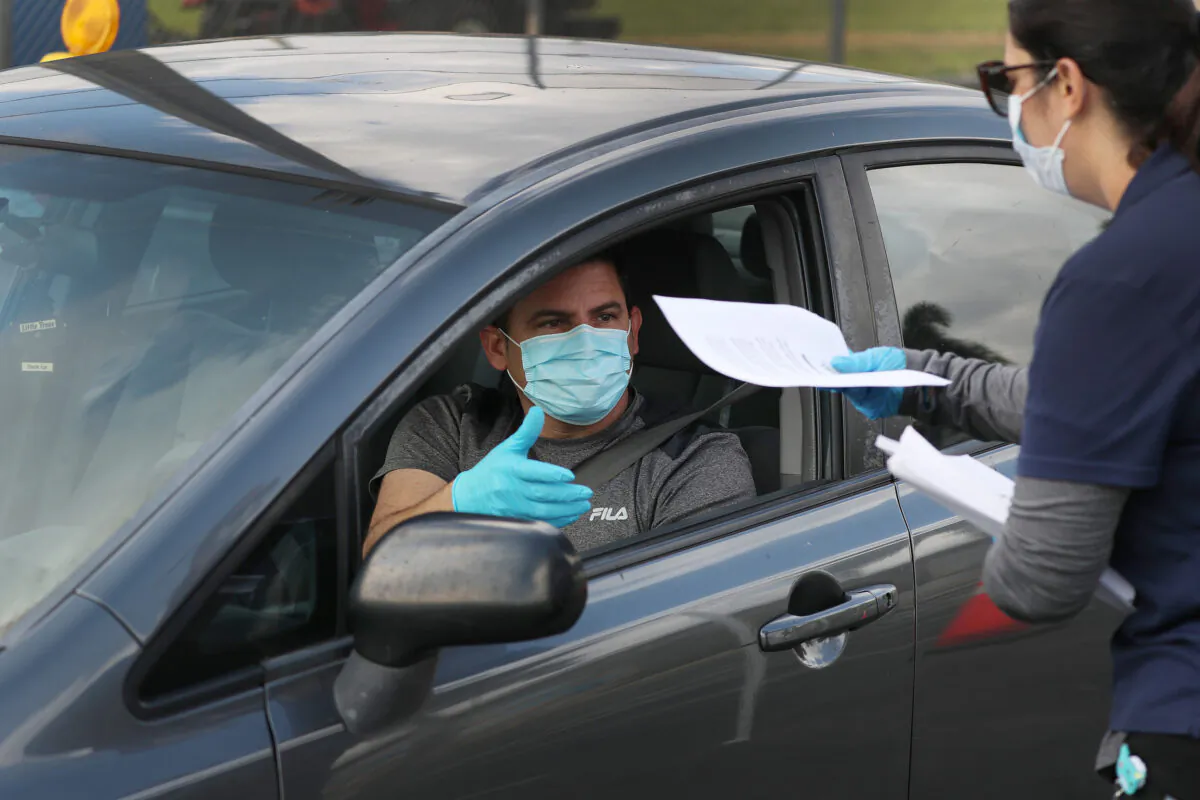 A person arrives in his car to receive an unemployment application being given out by city of Hialeah employees in front of the John F. Kennedy Library in Hialeah, Florida, on April 8, 2020. (Joe Raedle/Getty Images)