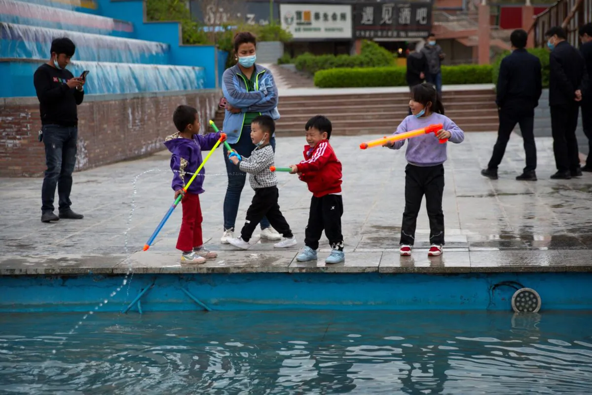 Children play with water toys at a public square in Aksu, Xinjiang Uyghur Autonomous Region, China, on April 20, 2021. (Mark Schiefelbein/AP Photo)