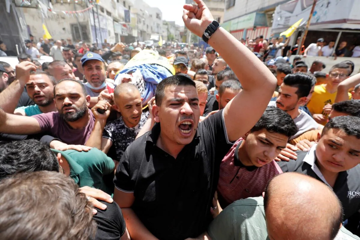 A mourner reacts as they carry the body of Palestinian man Hussien al-Titi, who was killed during stone-throwing clashes with Israeli forces, at Fawwar refugee camp near Hebron, in the Israeli-occupied West Bank, on May 12, 2021. (Mussa Qawasma/Reuters)
