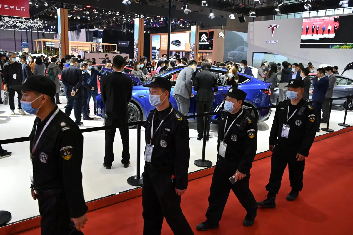 Guards walk near a Tesla stand during the 19th Shanghai International Automobile Industry Exhibition in Shanghai on April 19, 2021. (Photo by Hector RETAMAL / AFP) (Photo by HECTOR RETAMAL/AFP via Getty Images)