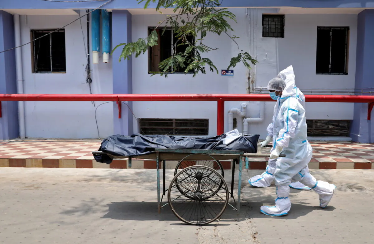 Healthcare workers transfer the body of a person who died from COVID-19, in Kolkata, India, on May 12, 2021. (Rupak De Chowdhuri/Reuters)