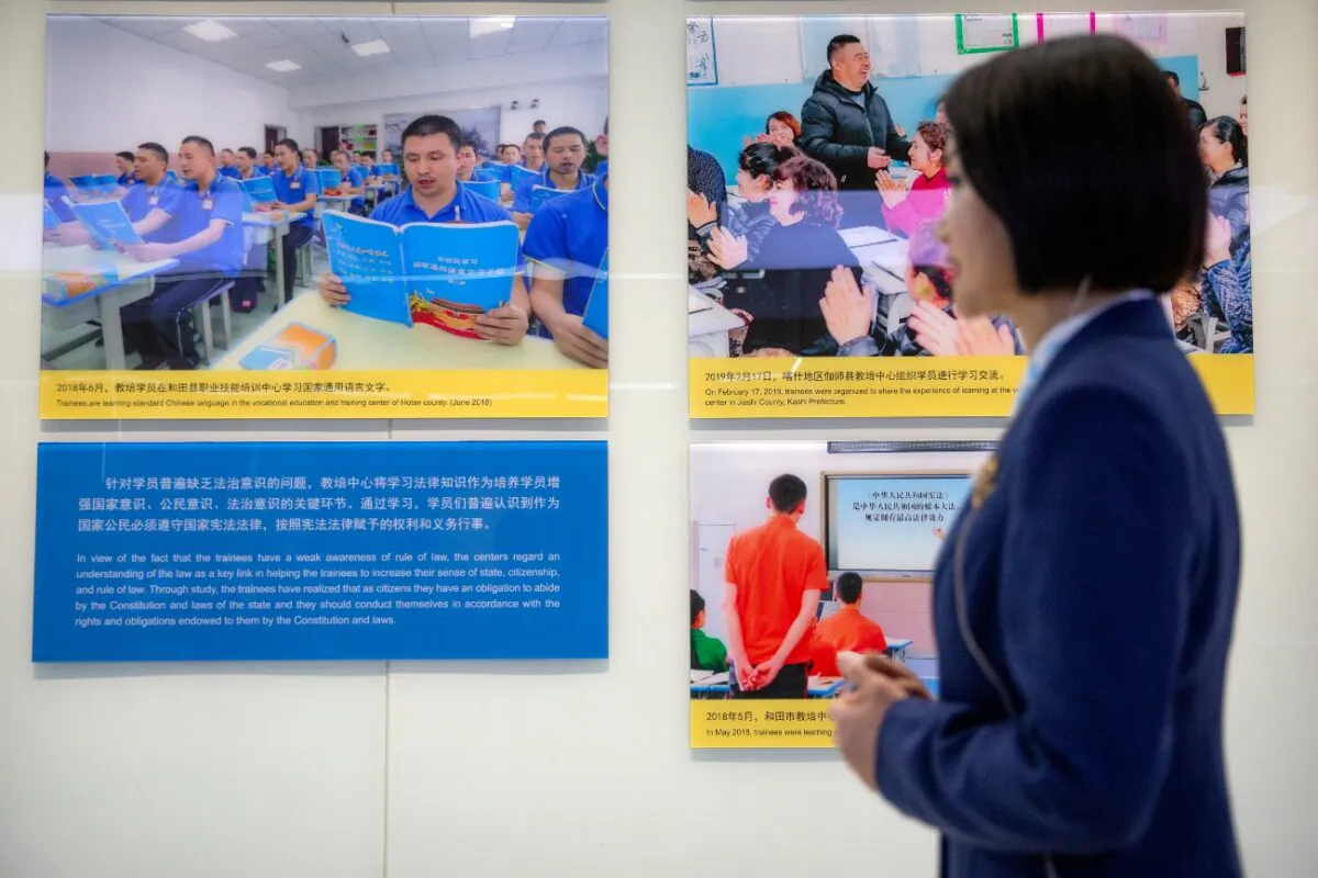 A tour guide stands near a display showing images of people at locations described as vocational training centers in southern Xinjiang at the Exhibition of the Fight Against Terrorism and Extremism in Urumqi in the Xinjiang Uyghur Autonomous Region in China on April 21, 2021. (Mark Schiefelbein/AP Photo)