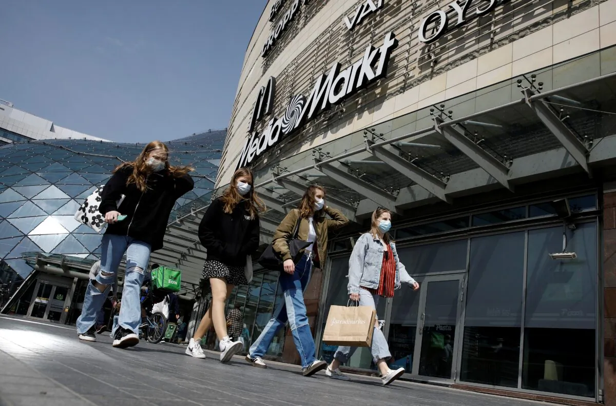 People wearing protecting masks walk in front of the Zlote Tarasy shopping mall in the centre of the city as the government eased COVID-19 restrictions, in Warsaw, Poland, on May 4, 2021. (Kacper Pempel/Reuters)