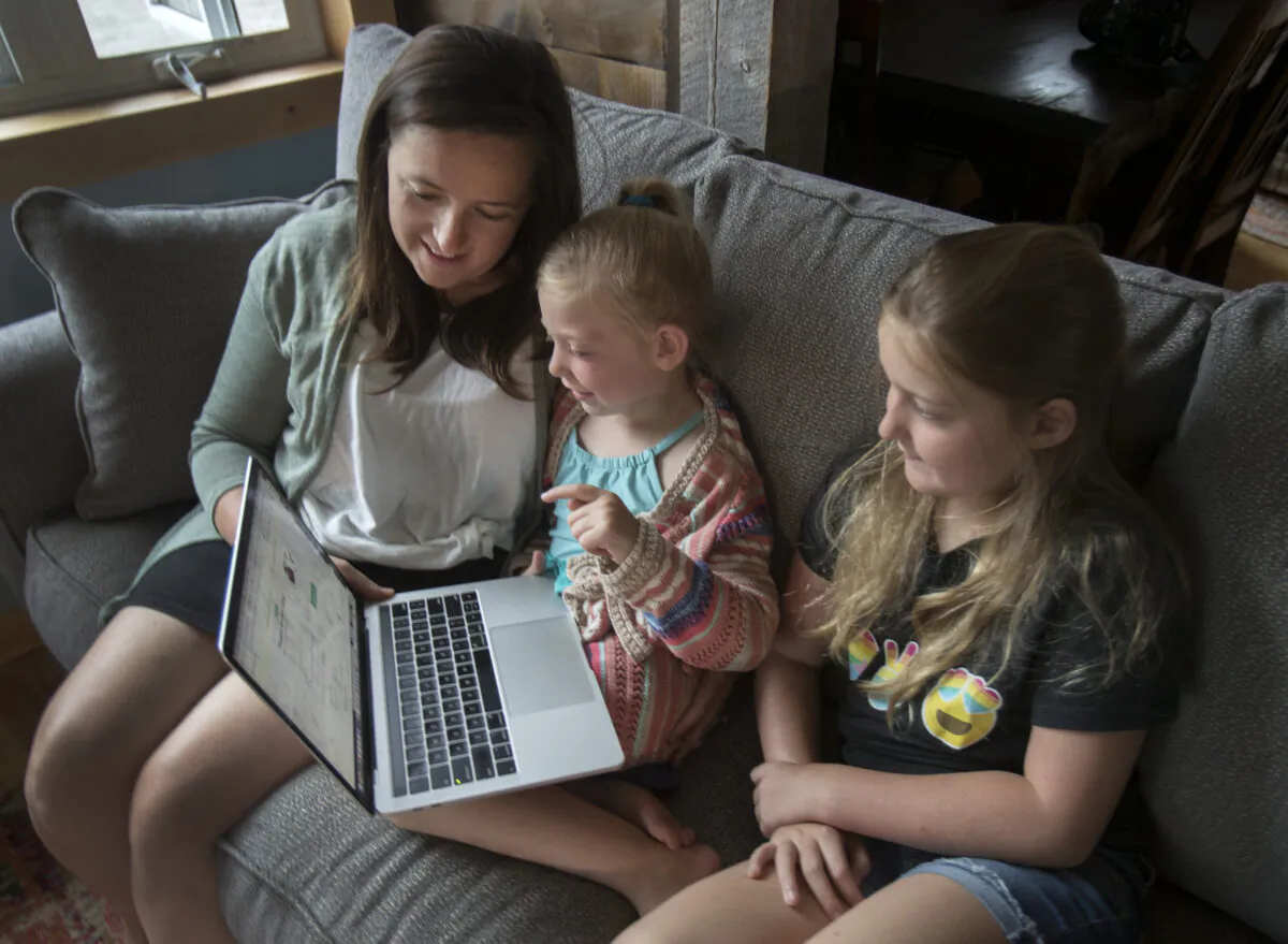 Andrea MacDonald with her daughters Rose, 5, and Grace, 9, take part online with Twitter's "virtual camp" at their summer residence in Harcourt, Ont., on August 2, 2020. (Fred Thornhill/The Canadian Press)