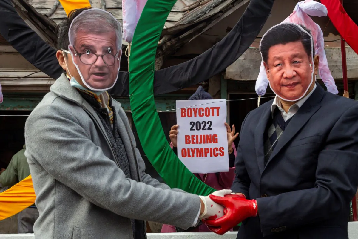 Activists wearing masks of IOC President Thomas Bach (L) and Chinese leader Xi Jinping pose in front of the Olympic Rings during a street protest against holding the 2022  Winter Olympics in China, in Dharmsala, India, on Feb. 3, 2021. (Ashwini Bhatia/AP Photo)